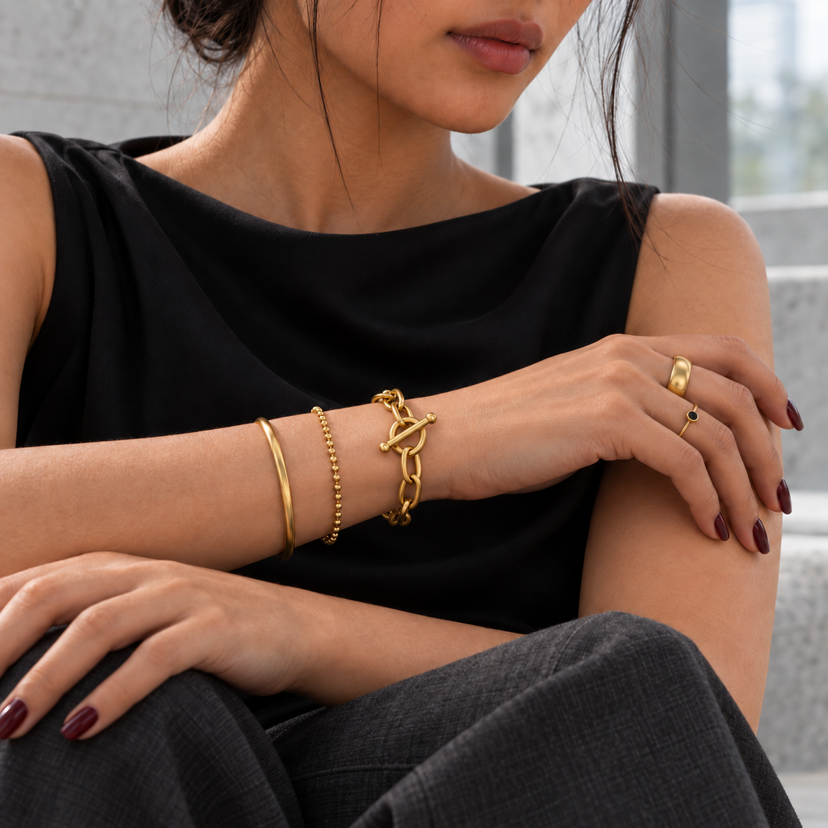 Verschiedene goldfarbene Armbänder und Ringe als harmonisches Stylingbeispiel